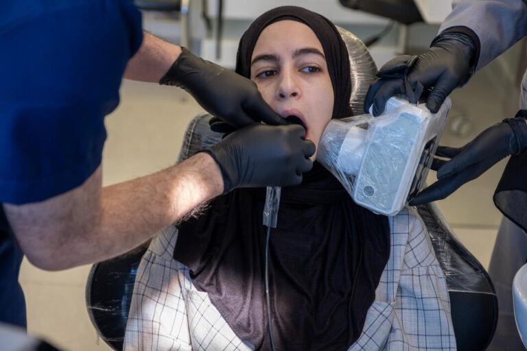 dentist-is-performing-dental-xray-female-patient-seated-dental-chair-patient-is-positioned-with-her-mouth-open-while-xray-device-is-held-place-capture-image_606429-4012