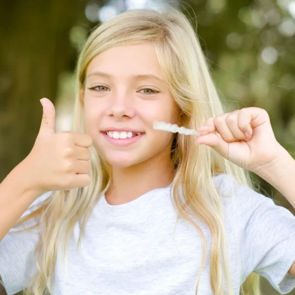 Smiling child wearing clear Invisalign aligners during orthodontic treatment.